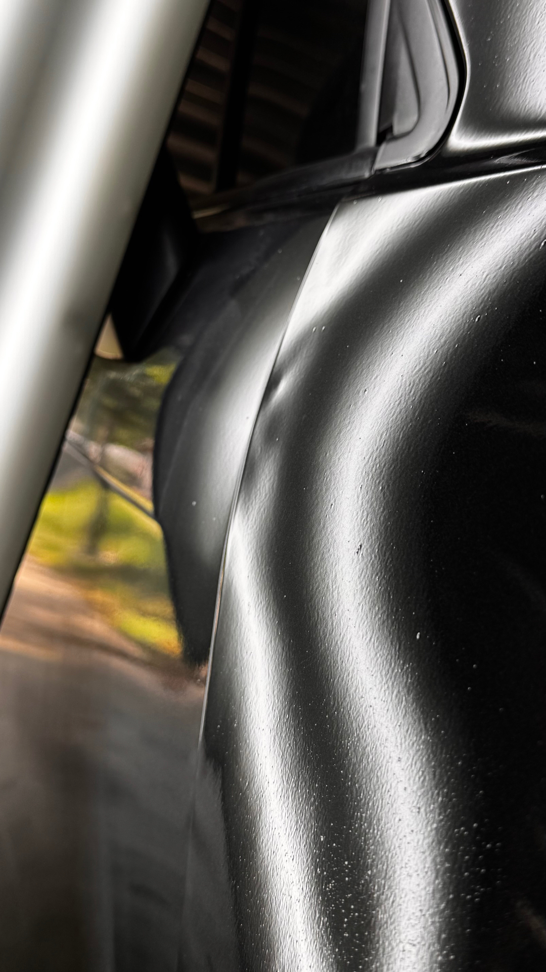 Door dent highlighted by reflection lines on black paint