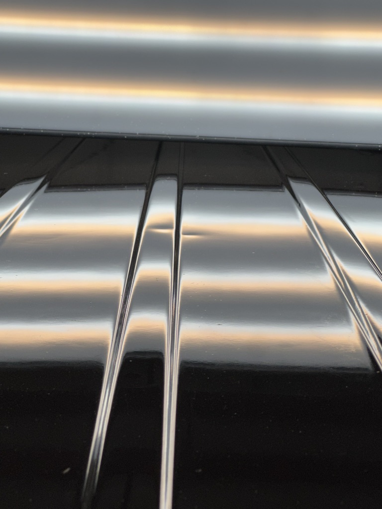 Dark roof panel inspected beneath warm PDR reflection lines