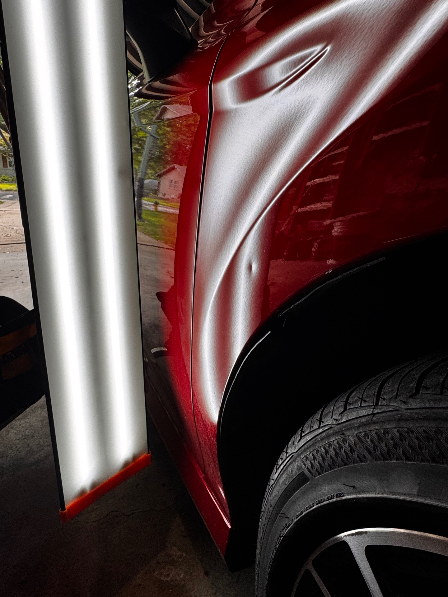 Sharp crease on a red rear quarter panel under PDR reflection lighting