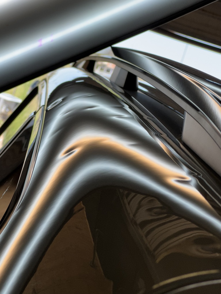 Deep dents along a glossy black roof edge under reflection lighting