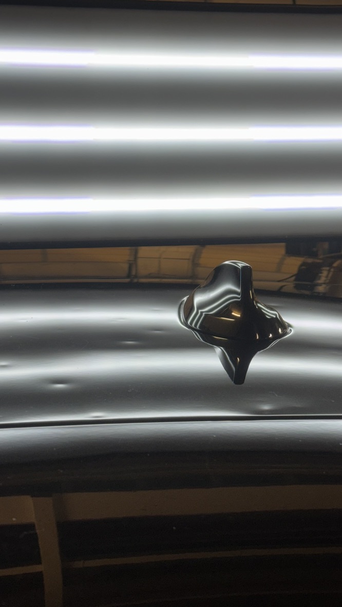 Hail dents surrounding a roof antenna under PDR reflection lighting